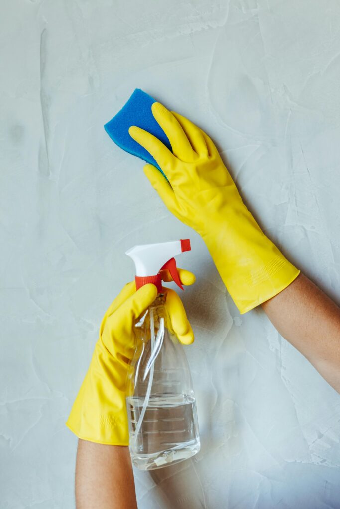 lawn-01 Hands in yellow gloves cleaning wall with sponge and spray bottle.